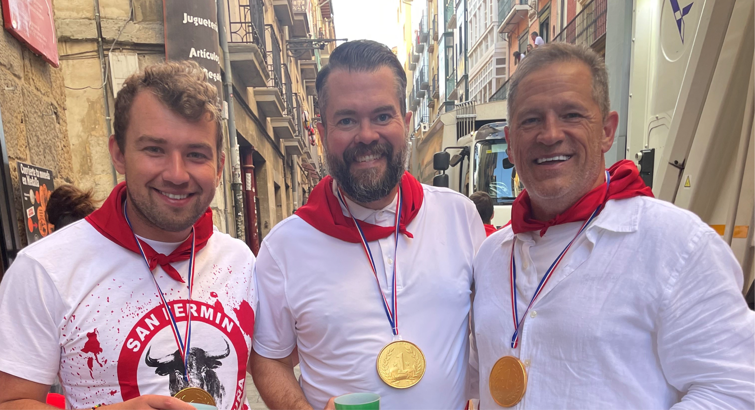 Bobby Saxon, right, celebrates with his stepson, Gage Wampler, left, a first lieutenant in the U.S. Army, and a friend, Greg Jacobson, in traditional white garb and red sashes after running with the bulls in Pamplona in July. Bobby convinced both to participate in the event. The medals are actually chocolate coins covered in gold foil. 